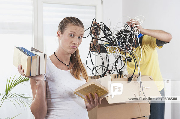 Confused pregnant woman packing with her husband while moving to new apartment