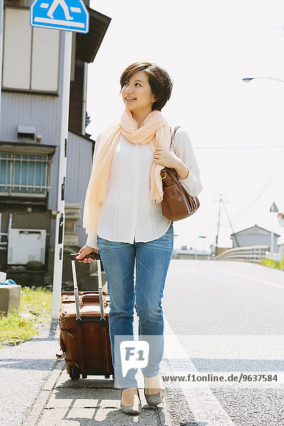 Young Japanese woman walking with suitcase