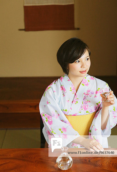 Young Japanese woman in a yukata drinking sake