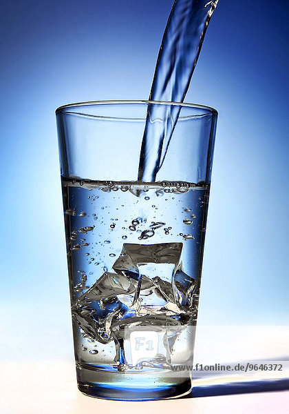 Wasser wird in ein Glas mit Eiswürfeln gegossen