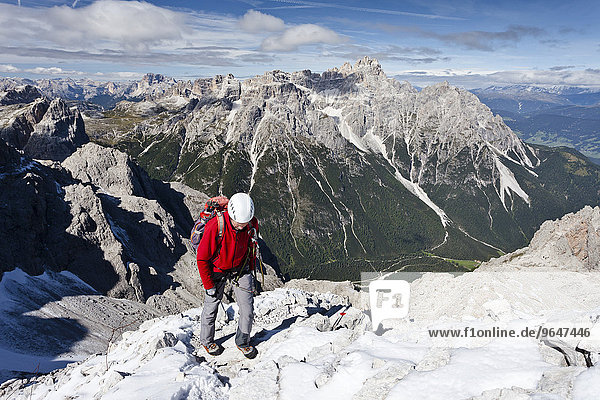 Bergsteiger beim Aufstieg über den Rotwandsteig auf die Sextner Rotwand in den Sextner Dolomiten  hier oberhalb der Rotwandwiesen  hinten die Dreischusterspitze  unten das Altsteintal  Hochpustertal  Südtirol  Trentino-Südtirol  Italien  Europa