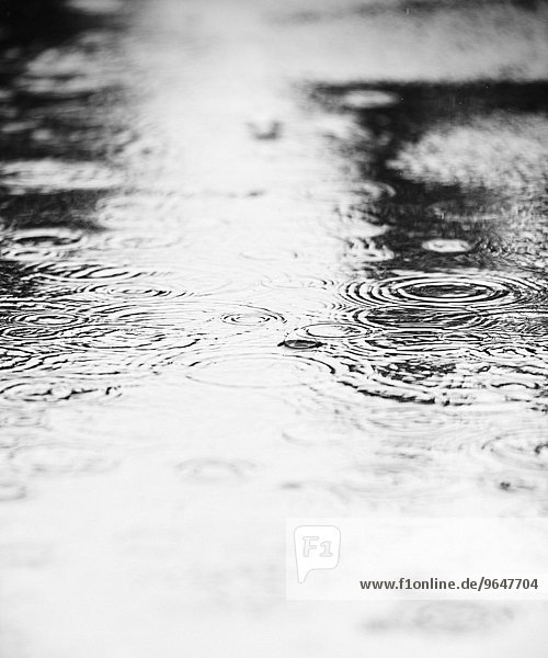 Wasserpfütze mit fallenden Regentropfen