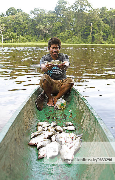 Fischer  28 Jahre  sitzt in einem Einbaumkanu und hält einen Roncador oder Süßwassertrommler in den Händen  Laguna Penitencia  Tortuguero-Nationalpark  Provinz Limón  Costa Rica  Nordamerika