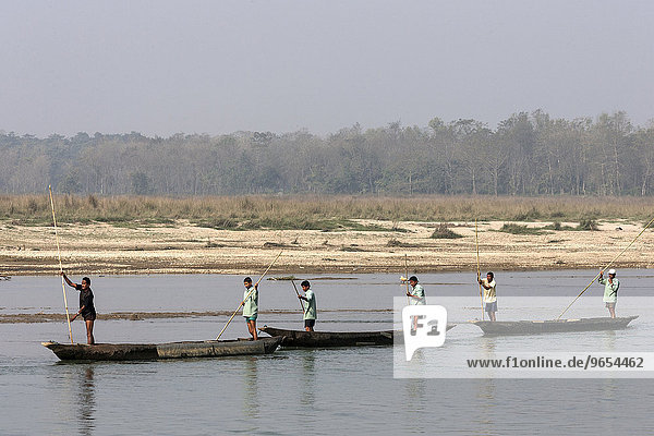 Nepalese men in dugouts on the East Rapti River at Sauraha  Nepal  Asia