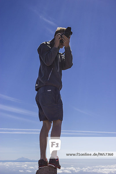 'Junger Mann fotografiert,  steht auf Stein,  dahinter Insel Teneriffa mit Teide,  ''Ruta de los Volcanes'',  Vulkanroute,  Naturpark Cumbre Vieja,  La Palma,  Kanarische Inseln,  Spanien,  Europa'