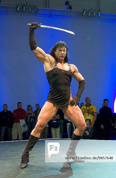 Bodybuilderin posiert mit Schwert auf der Fitnessmesse FIBO in Essen
