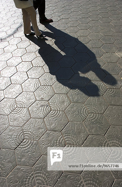 Spaziergaenger werfen Schatten auf die von Antonio Gaudí entworfenen Fliesen mit denen der Buergersteig des Paseo de Gracia (Paseig de Gracia) gepflastert ist in Barcelona  Spanien  Europa
