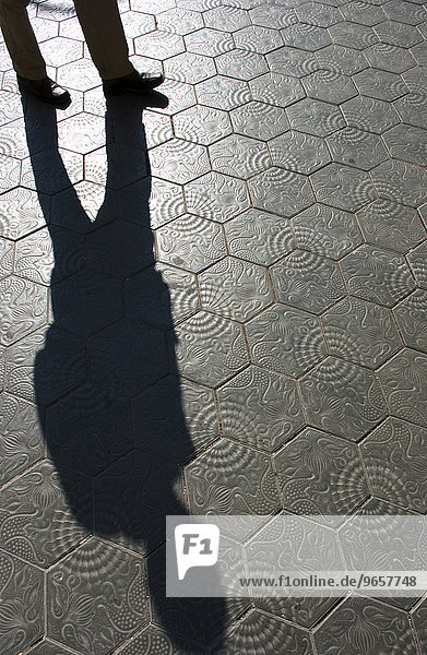 Ein Spaziergaenger wirft seinen Schatten auf die von Antonio Gaudí entworfenen Fliesen mit denen der Buergersteig des Paseo de Gracia (Paseig de Gracia) gepflastert ist in Barcelona  Spanien  Europa