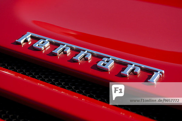 Ferrari Schriftzug auf der Motorhaube eines Sportwagens der italienischen Edelmarke im typischen rot