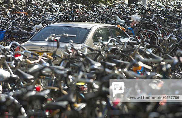 Ein Auto verschwindet fast im Meer von geparkten Fahrrädern vor dem Hautbahnhof von Amsterdam  Niederlande  Europa