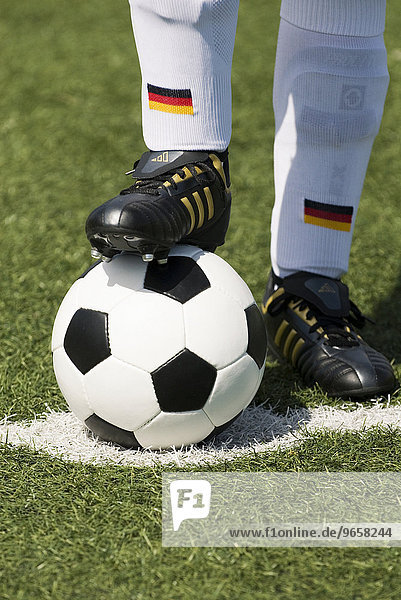 Feet of a German national football player and a classic black-and-white football