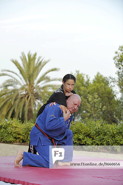 Eine Frau und ein Mann beim Kampfsport-Training in einem Park