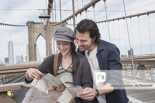 Happy couple reading map on Brooklyn Bridge