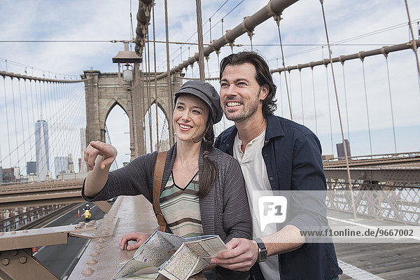 Happy couple with map on Brooklyn Bridge