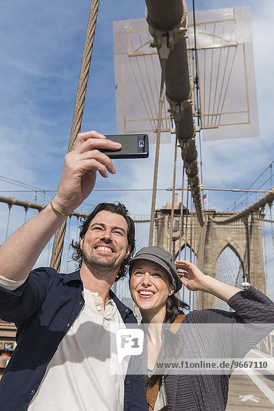 Happy couple taking selfie on Brooklyn Bridge