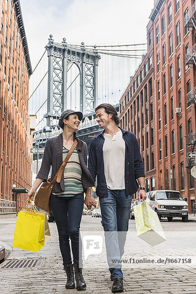 Couple walking on street  Brooklyn Bridge in background