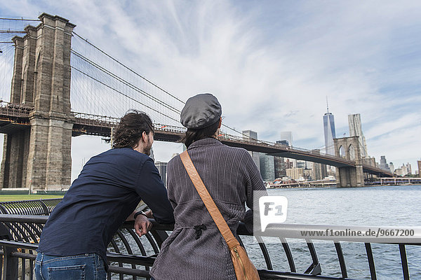 Couple leaning against railing and looking at Freedom Tower