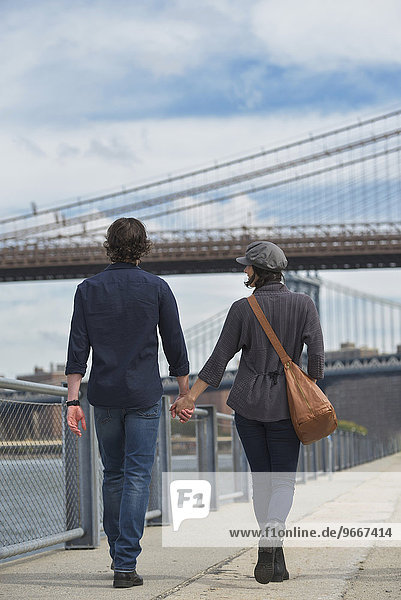 Rear view of couple walking on promenade  Brooklyn Bridge in background