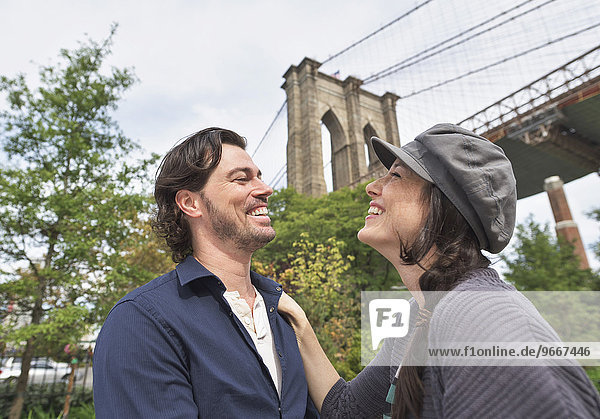 Happy couple standing against Brooklyn Bridge