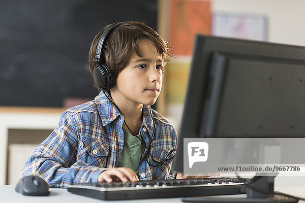 Schoolboy (6-7) using computer in classroom