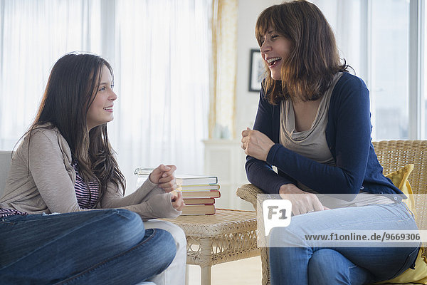 Teenage girl (14-15) talking with her mom in living room