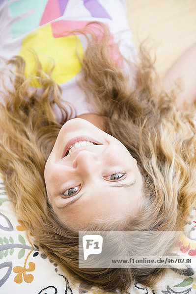 Portrait of smiling teenage girl (12-13) lying on pillow