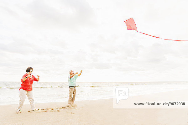 Couple flying kite together on beach