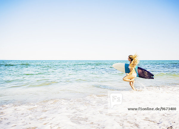 junge Frau junge Frauen tragen rennen Surfboard Wellenreiten surfen Brandung Meer