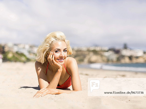 Portrait of blond woman lying on beach