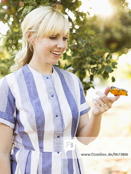 Portrait of blond woman with butterfly in orchard