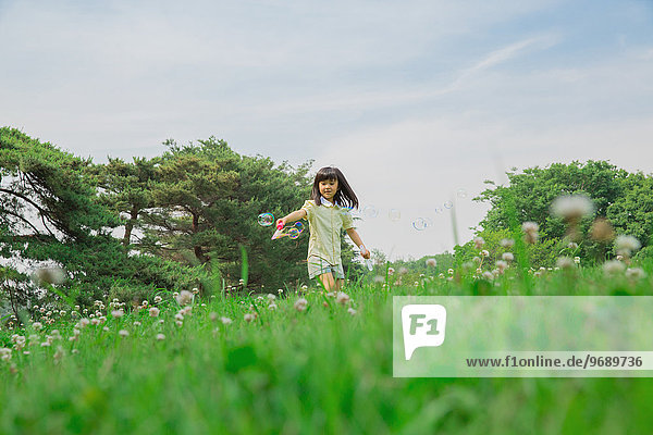 Japanese kid playing with soap bubbles in a park