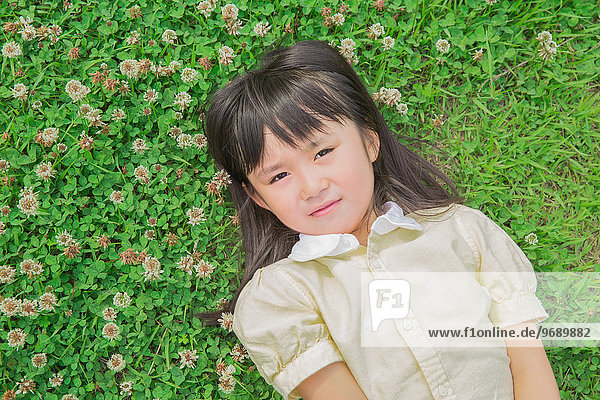 Japanese kid laying on grass in a park