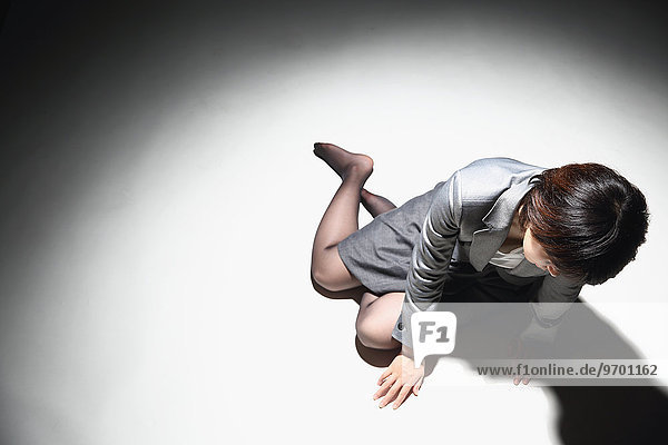 Japanese businesswoman in a suit laying on the ground