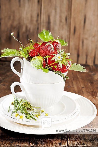 Erdbeeren mit Blüten und Blättern in Tasse