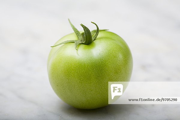 Eine grüne Tomate auf Marmorplatte