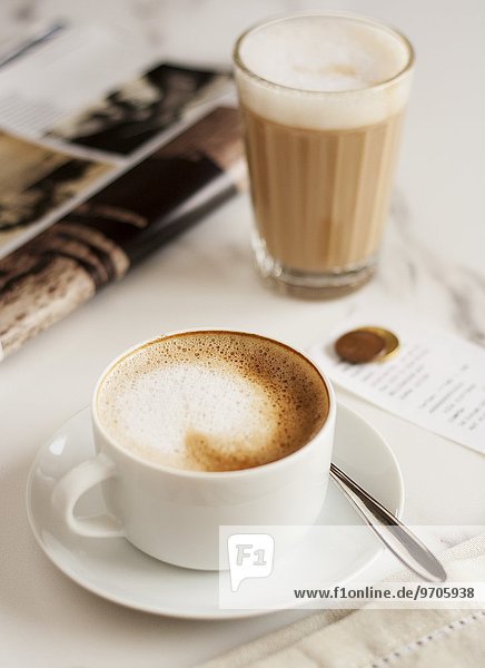 Cappucino und Caffe Latte neben einer Zeitschrift