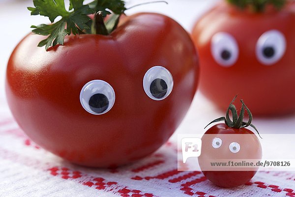 Tomatenfamilie mit Gesicht auf rustikalem Tischtuch