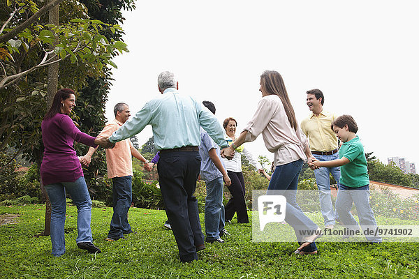 Hispanic family holding hands in a circle outdoors