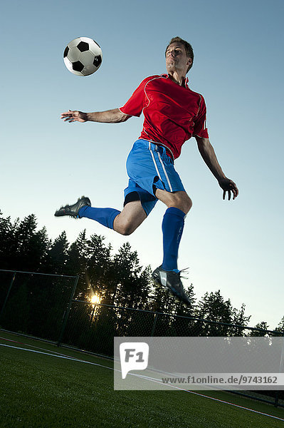 Fußballspieler treten springen Ball Spielzeug In der Luft schwebend