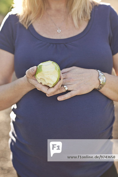 Außenaufnahme Europäer Frau Schwangerschaft Apfel essen essend isst freie Natur