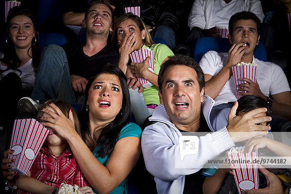 Frightened Hispanic family watching film in movie theater