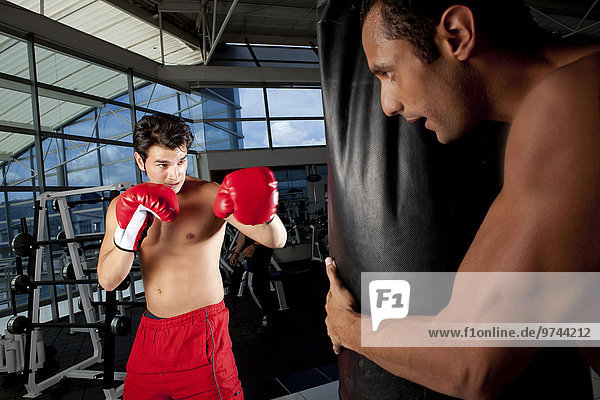 Hispanic man using punching bag in health club