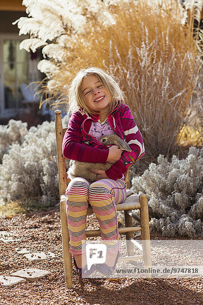 Caucasian girl smiling in chair outdoors