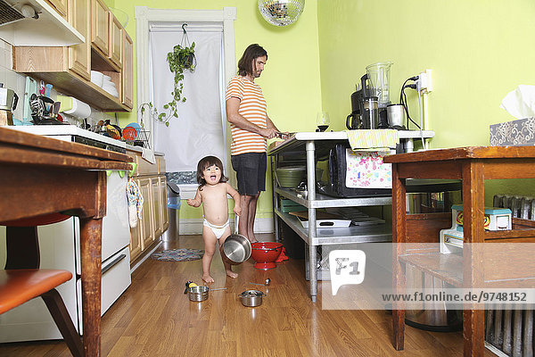Girl playing in kitchen as father cooks