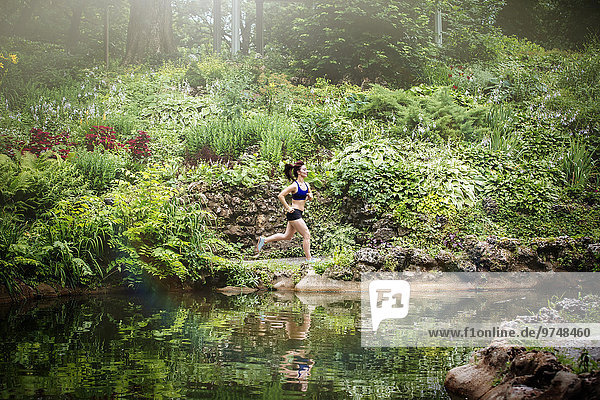 Caucasian woman running near lake in park