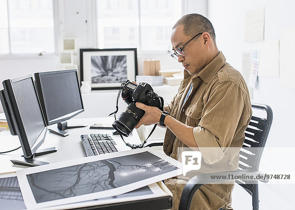 Korean photographer using camera at desk