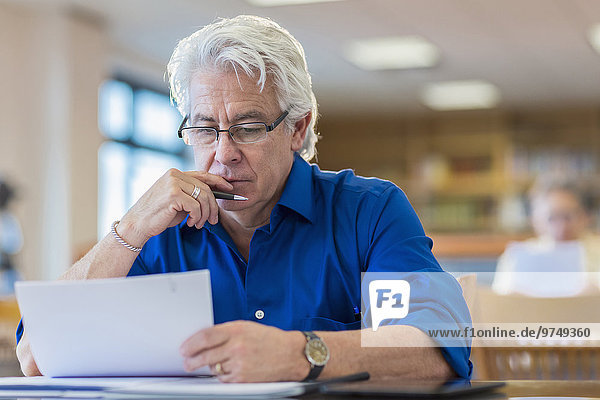 Man reading paperwork in library