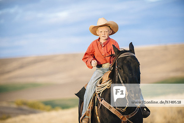 Caucasian boy riding horse in grassy field
