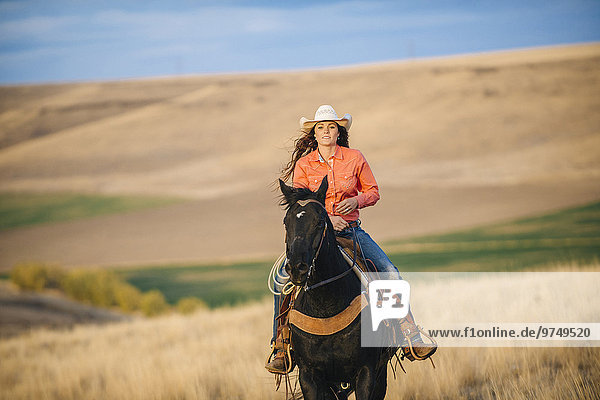 Caucasian woman riding horse in grassy field