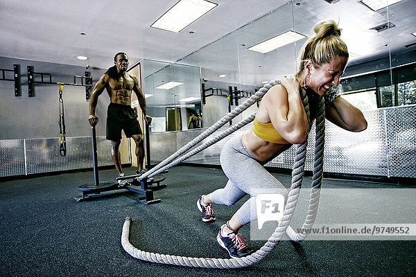 People working out with ropes in gym